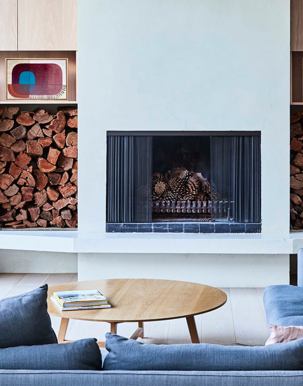 Modern living room with a fireplace, blue sofa, and wooden coffee table.
