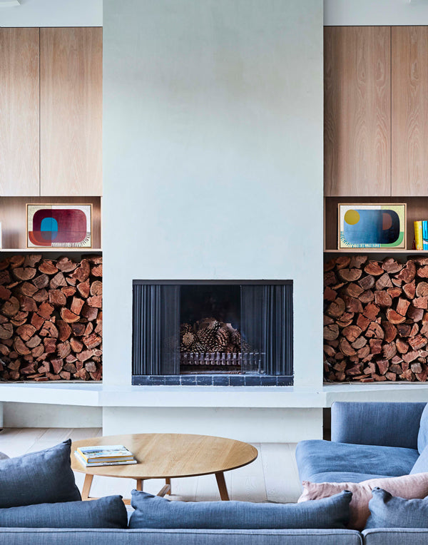 Modern living room with a fireplace, blue sofa, and wooden coffee table.