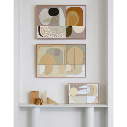 Two framed abstract Giclee prints on an end table, with one featuring a buttery color palette and the other with a more muted color scheme.