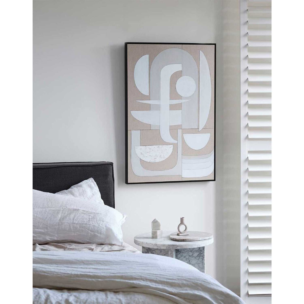A framed Giclee print featuring a geometric pattern with abstract elements, displayed above a bed in a room with arched windows and a white headboard.